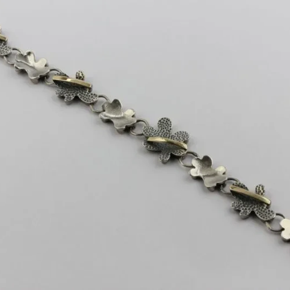 Браслет из серебра 925 пробы с цветочным узором и золотой отделкой.
