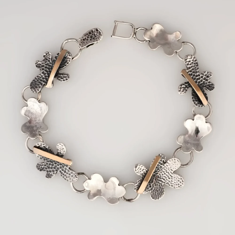 Браслет из серебра 925 пробы с цветочным узором и золотой отделкой.